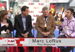 Four people sit in a row during an interview session with a red and white backdrop.