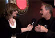 A woman holding a microphone toward a man during an interview.