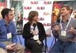 A man in a blue shirt, a woman in a black cardigan, and a man in a grey shirt sitting in a panel discussion.