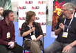 A man in a maroon shirt, a woman in a black top, and a man in a black t-shirt sit for an interview.