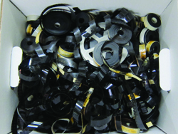 A white box overflowing with numerous rolls of black adhesive tape of different sizes.