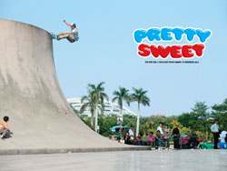 A person mid-air on a skateboard at the top of a large concrete skate ramp under a blue sky.