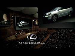 A large presentation screen displays a silver Lexus SUV above an audience in a dark auditorium.