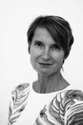 Black and white portrait of a woman with short hair wearing a patterned shirt against a white background.