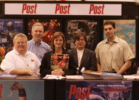 Five people smiling behind a counter with Post magazine displays and posters.