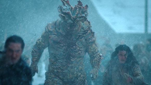 A large, humanoid creature with bumpy, organic skin stands in a snowy crowd.