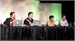 Four people sit behind a long table with laptops and microphones during a panel discussion.