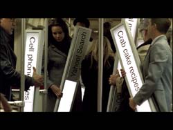 People walk between tall, glowing pillars displaying text like 'Cell phone' and 'Crab cake recipes'.